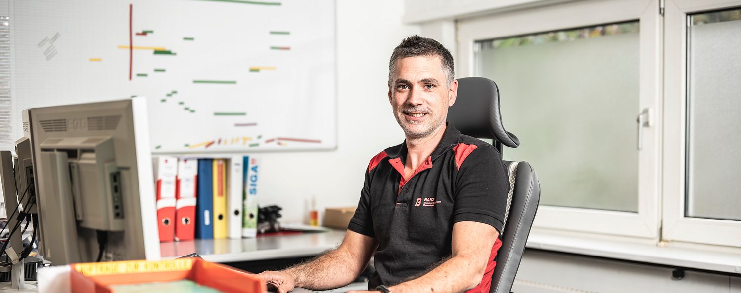 Projektleiter Andreas im Büro am Schreibtisch vor dem Computer.