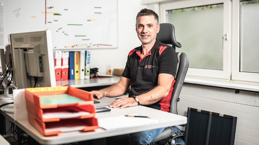 Projektleiter Andreas im Büro am Schreibtisch vor dem Computer.