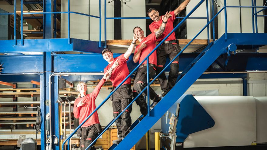 Team auf der Brücke mit Armbewegung in Treppenrichtung aufwärts.