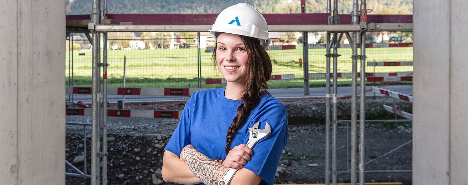 Sanitärinstallateurin mit Schraubenschlüssel in der Hand. Steht auf der Baustelle.